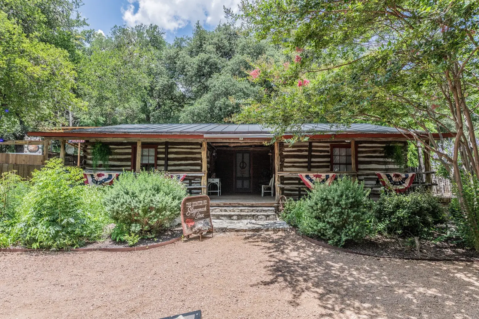 Row of historic timber buildings framed by live oaks and native landscaping