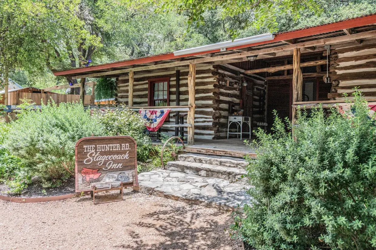 Hand-hewn log building frontage with a stone path and native plantings