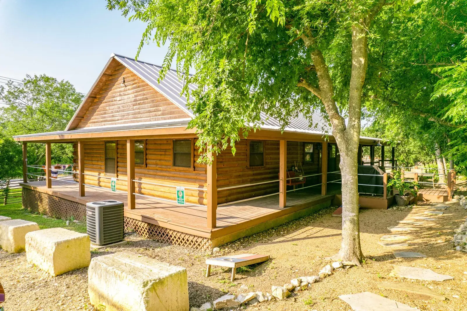 Cedar cabin suite with a wraparound porch under shade trees