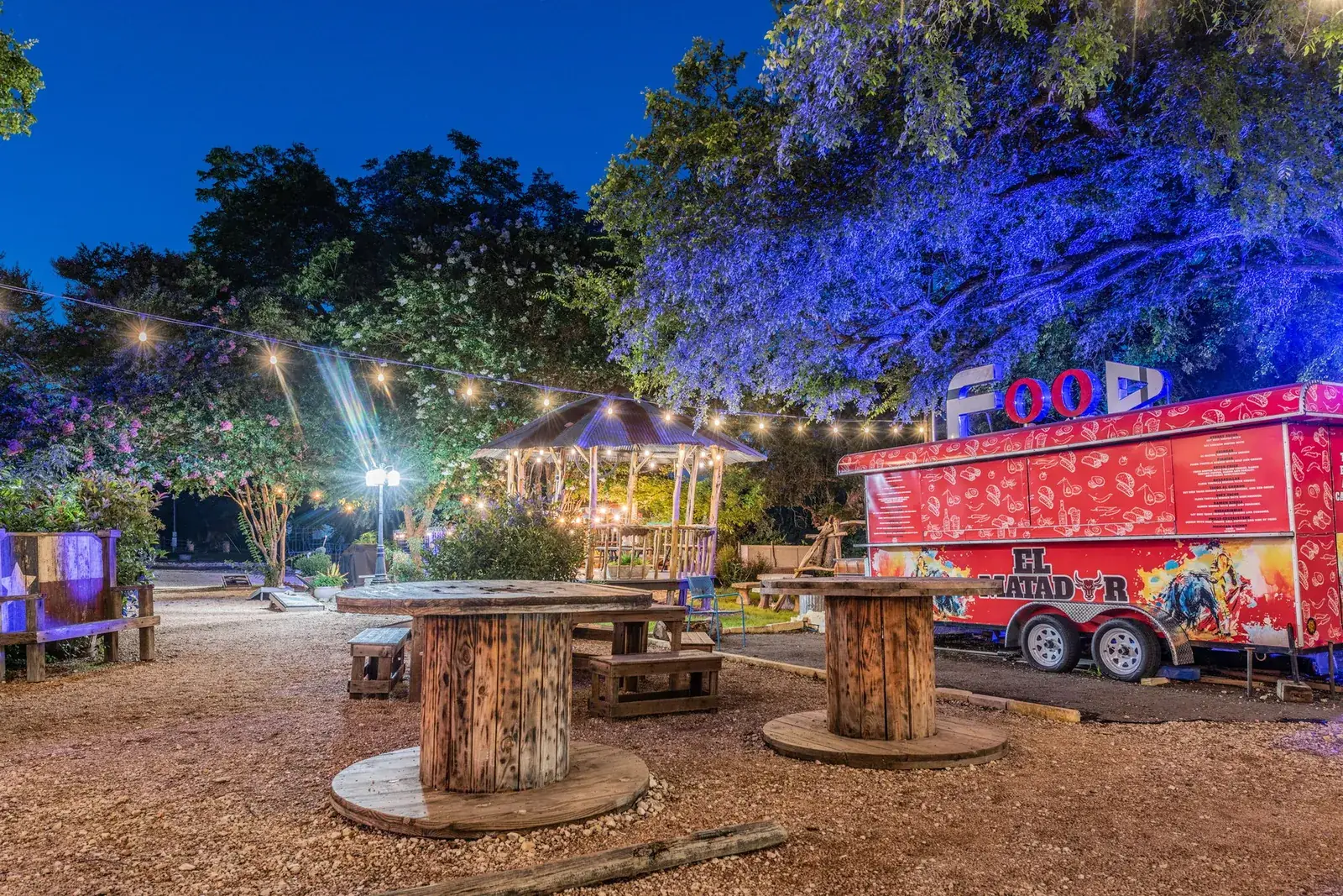 Lantern-lit courtyard with string lights and outdoor seating at a mixed-use property in New Braunfels at dusk