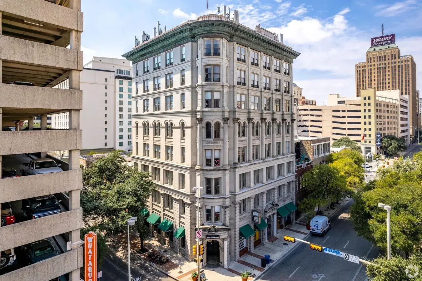 Historic eight-story stone office building with green awnings on a downtown San Antonio corner